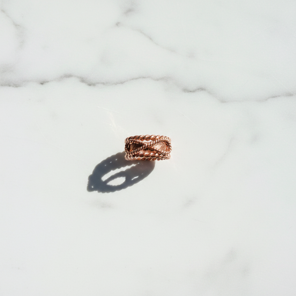 Flat lay top-down view of copper tensor ring on white marble