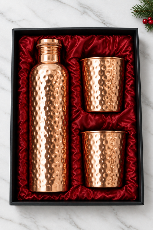 Hammered copper screw-cap bottle and two shorter, wider hammered tumblers in a red-lined black gift box